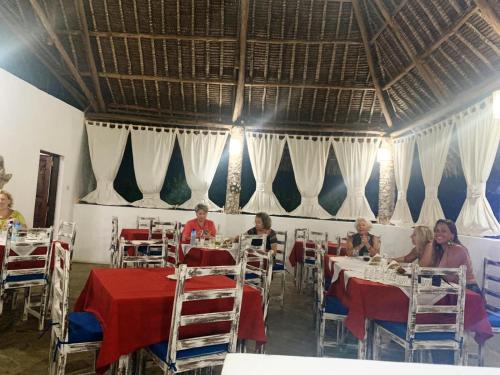 a group of people sitting at tables in a restaurant at BeB Sardegna2 Anjumasa village in Watamu