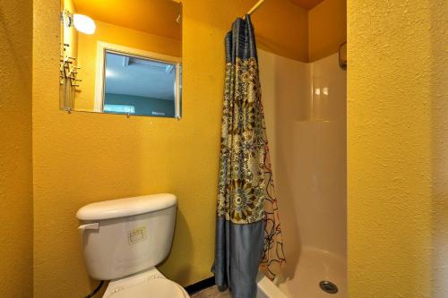a yellow bathroom with a toilet and a shower at Seward Studio with Deck, Outdoor Dining and Mtn Views! in Seward