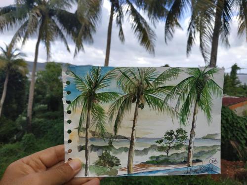 a person holding up a picture of palm trees at Meryem in La Trinité