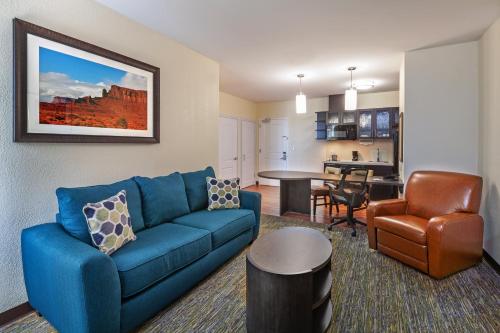 a living room with a blue couch and a kitchen at Candlewood Suites Houston - Spring by IHG in Houston