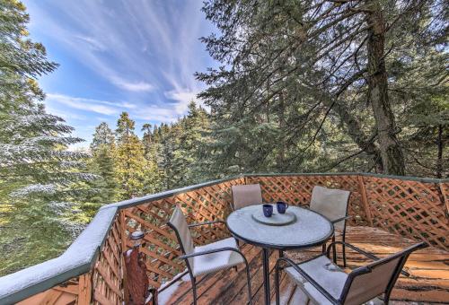 a table and chairs on a balcony with trees at Lake Arrowhead Cabin with Deck and Scenic Forest Views in Lake Arrowhead