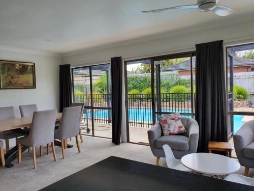 a living room with a table and chairs and a view of a pool at Kerikeri Central House in Kerikeri