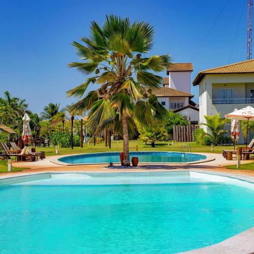 a pool with a palm tree in front of a house at Tree Bies Resort - Oficial in Subaúma