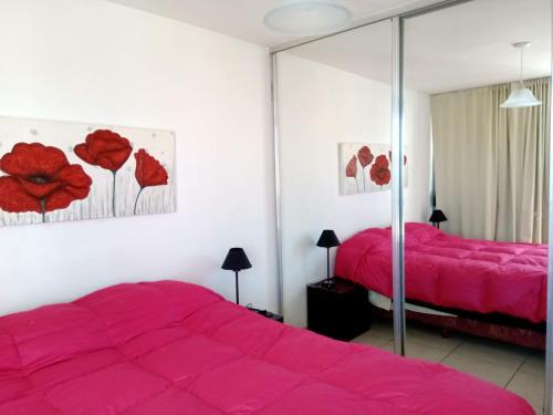 1 dormitorio con cama rosa y espejo en Departamento Luxor en Villa Carlos Paz