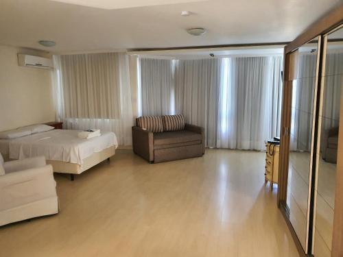 Manhattan Apart Hotel في بورتو أليغري: غرفة نوم بسرير واريكة وكرسي