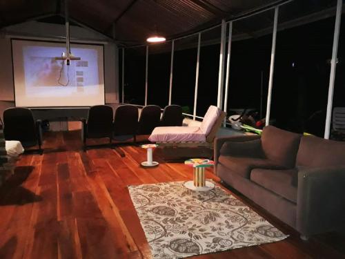a room with a couch and a stage with a screen at Madre Selva Hostel in Puerto Viejo