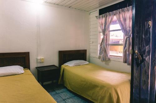 two beds in a room with a window at Cabinas EL PRADO in San Isidro