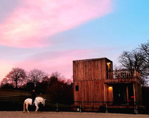 a person riding a horse in front of a building at Manège de la Chapinière - DadaLoge tiny-house in Châteauvieux