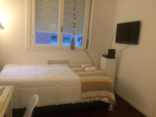 a white bedroom with a bed and a window at Monoambiente in Buenos Aires