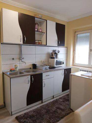 a kitchen with white and black cabinets and a microwave at Apartment Zabljak Center in Žabljak
