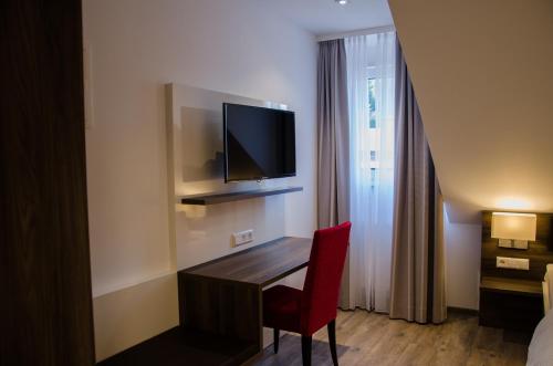 a hotel room with a desk with a television on the wall at Hotel Restaurant Lamm in Mönsheim