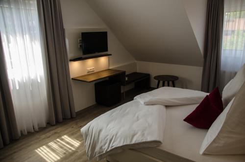 a bedroom with a bed and a desk with a television at Hotel Restaurant Lamm in Mönsheim