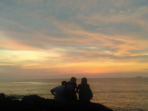 a group of people sitting on a rock looking at the ocean at Som PalmGarden in Ko Lanta