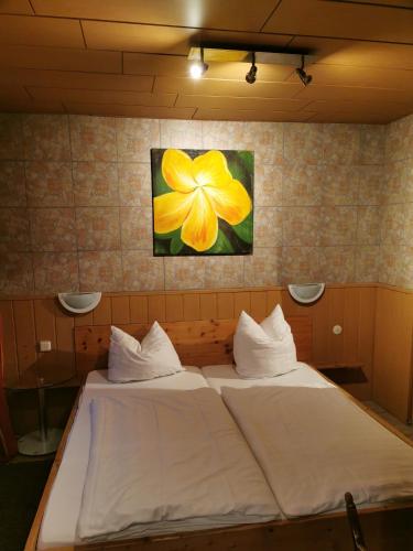 a bed in a room with a yellow flower on the wall at See Lord Hotel in Kaiserslautern