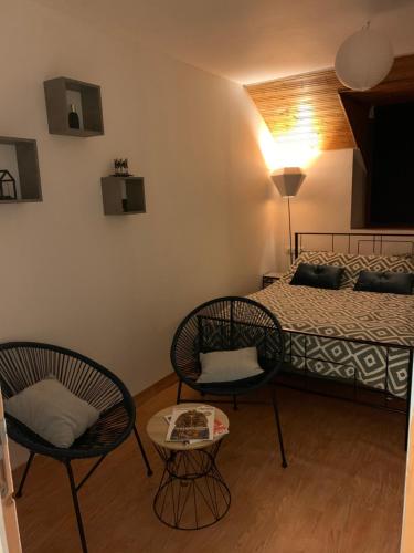 a bedroom with a bed and two chairs and a table at Accueil chaleureux in Crannes-en-Champagne