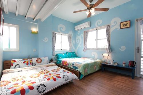 a bedroom with two beds and a ceiling fan at La Pace Hostel in Taitung City