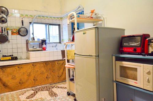 eine Küche mit Kühlschrank und Mikrowelle in der Unterkunft La Pace Hostel in Taitung