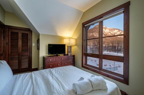 um quarto com uma cama e uma grande janela em Étoile du Matin by Rendez-Vous Mont-Tremblant em Mont-Tremblant