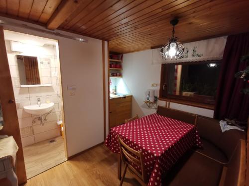 Cette chambre comprend une table et une salle de bains pourvue d'un lavabo. dans l'établissement Apartment Zalokar, à Bohinj