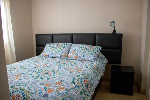 a bed with a quilt and a pillow on it at Departamento 100 m2 con luz natural Seguridad 24h in Lima