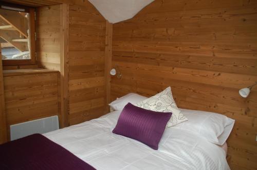 een slaapkamer met een wit bed en een paars kussen bij Two Bedroom Apartment La Voute, Chandon near Meribel - Sleeps 4 Adults or 2 Adults and 3 Children in Les Allues