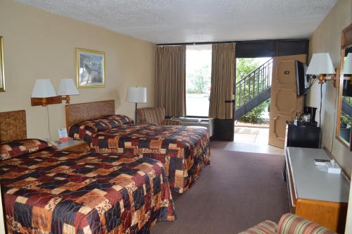ターポン・スプリングスにあるTarpon Shores Innのベッド2台とバルコニーが備わるホテルルームです。
