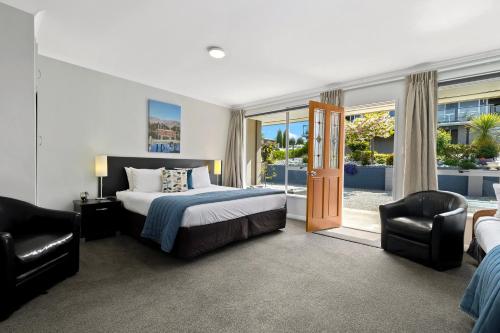 a bedroom with a king sized bed and two chairs at Central Gateway Motel in Cromwell