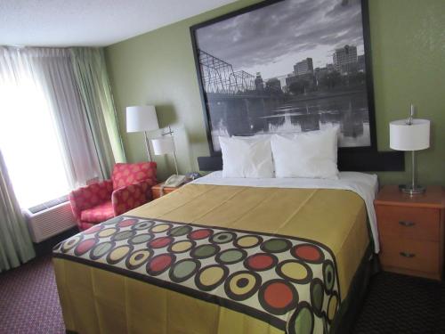 a hotel room with a large bed and a chair at Super 8 by Wyndham New Cumberland in New Cumberland