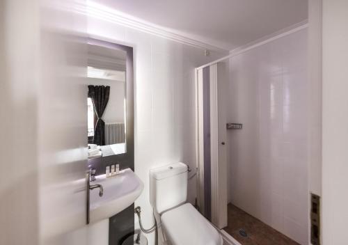 a bathroom with a toilet and a sink and a mirror at White Hills Suites & Spa in Arachova