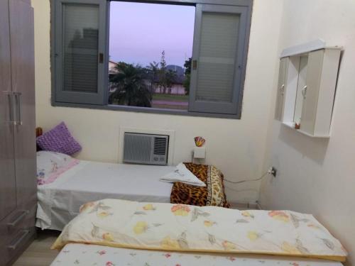 two beds in a room with a window at Santa Rosa do Sul - SC in Sombrio