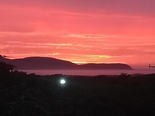 a sunset with the sun in the sky over the ocean at Pousada Recanto Devas in Cabo Frio