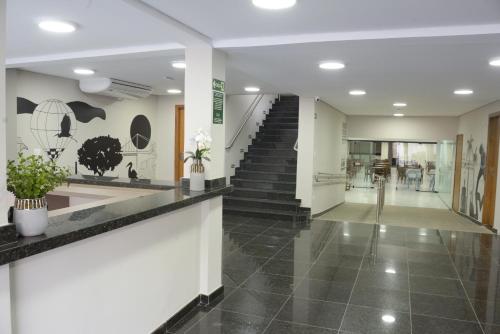 a hallway with a staircase and a lobby with black tiles at Asa Hotel in Piracicaba