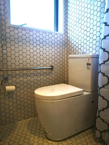 a white toilet in a bathroom with a window at V Motel in Christchurch