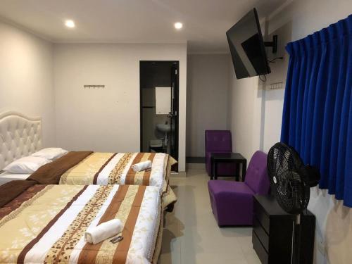 um quarto de hotel com duas camas e uma cadeira roxa em Bella Durmiente Hotel & Eventos em Chincha Alta