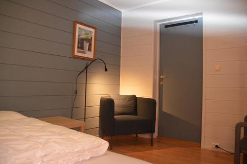 a bedroom with a bed and a chair next to a door at Haugo utleige lodge in Vossevangen