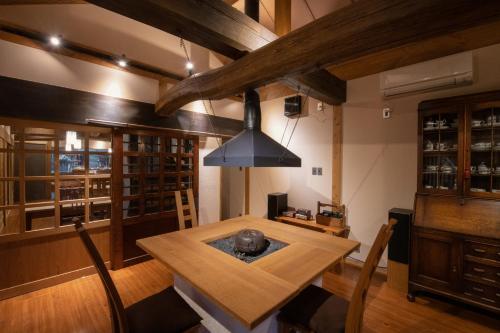 une salle à manger avec une table en bois et un lustre dans l'établissement inn NOSHIYU, à Minamioguni