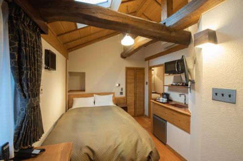 a bedroom with a bed and a desk and a tv at inn NOSHIYU in Minamioguni