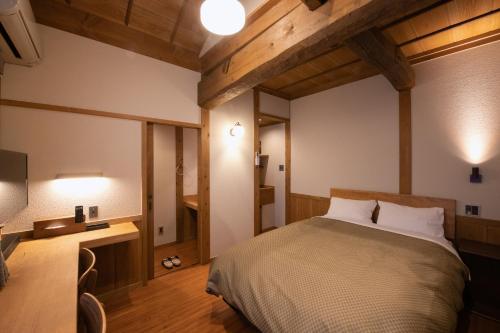 a bedroom with a bed and a desk and a television at inn NOSHIYU in Minamioguni