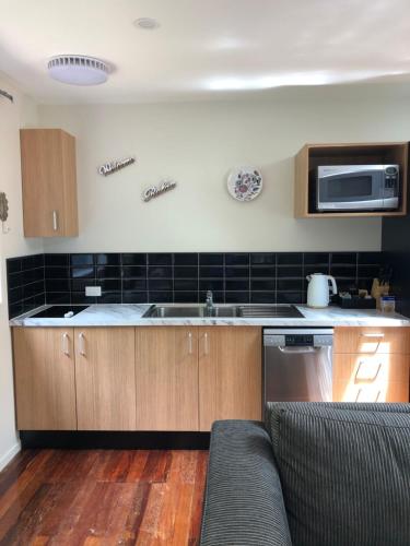 a kitchen with a couch and a sink and a microwave at Kānuka Cottage - Tranquil and relaxing in Akaroa
