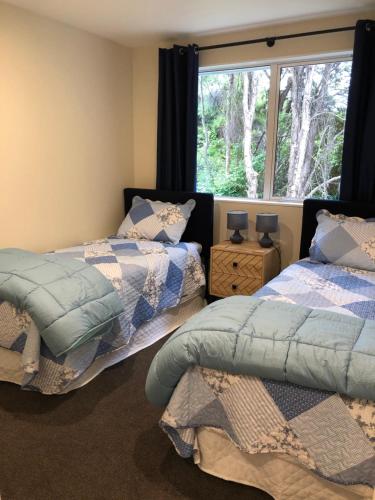 two beds in a room with a window at Kānuka Cottage - Tranquil and relaxing in Akaroa