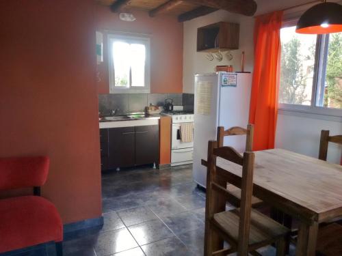 a kitchen with a wooden table and a refrigerator at Cabaña Las hermanas in Capilla del Monte