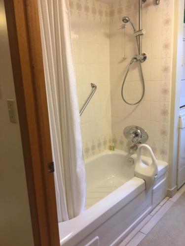 La salle de bains est pourvue d'une baignoire et d'une douche avec rideau de douche. dans l'établissement Burken B&B, à Brighton