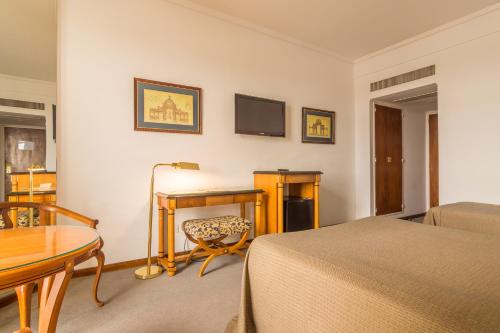 a bedroom with a desk and a bed and a table at Hotel Libertador in Tandil