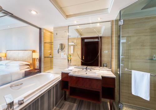 a bathroom with a tub and a sink and a bed at Maison New Century Hotel Ningbo in Ningbo
