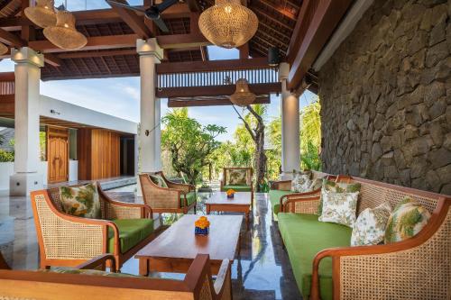 an outdoor patio with chairs and tables and a stone wall at Adiwana Unagi Suites in Ubud