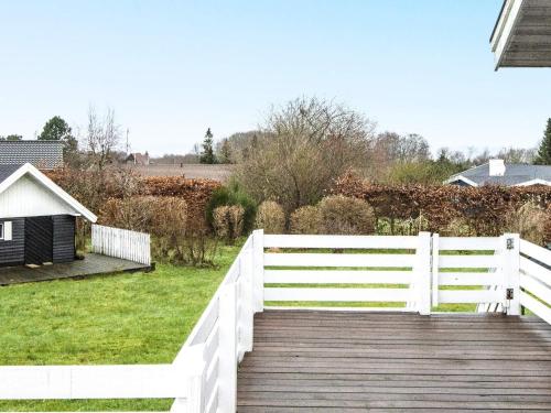 a wooden boardwalk leading to a yard with a white fence at 6 person holiday home in Glesborg in Glesborg