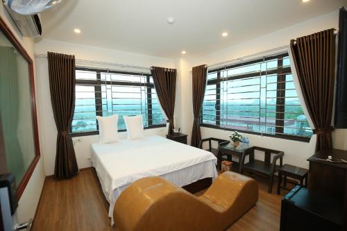 sypialnia z łóżkiem, krzesłem i oknami w obiekcie Việt Anh Hotel w mieście Ninh Binh
