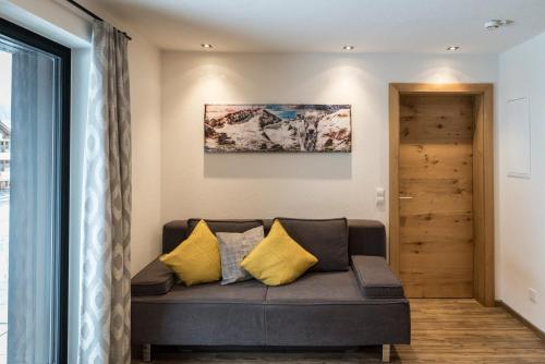 a living room with a couch with yellow pillows at Biwak Appartements in Sankt Anton am Arlberg