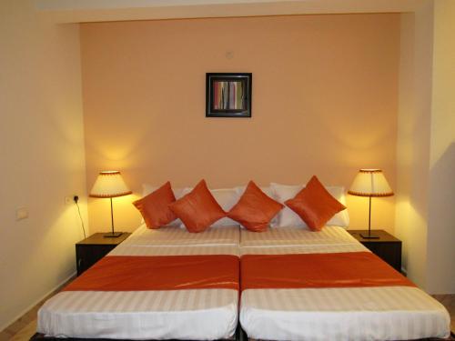 a bedroom with a bed with orange and white pillows at TGF Dream Guest House in Majorda