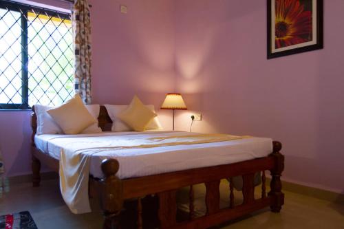 a bedroom with a large bed with a lamp on it at TGF Dream Guest House in Majorda